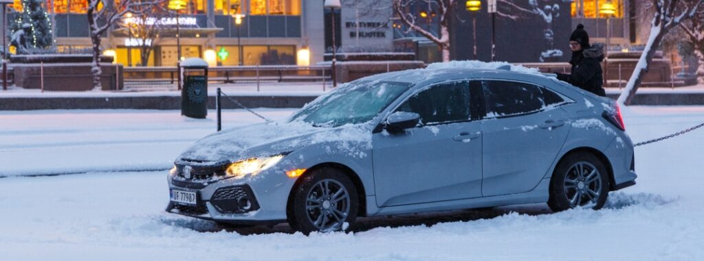 woman cleaning honda vehicle in snow
